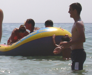 bañistas en una playa con una balsa hinchable